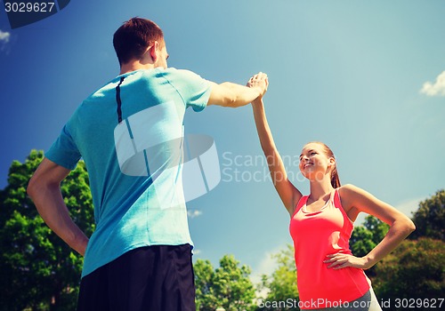 Image of two smiling people making high five outdoors