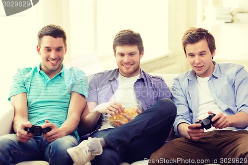 Image of smiling friends playing video games at home