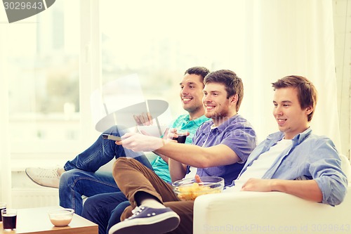 Image of smiling friends with remote control at home