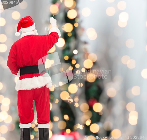 Image of man in costume of santa claus writing something