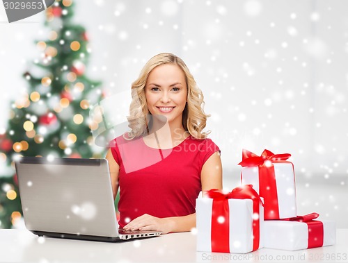 Image of woman with gift boxes and laptop computer