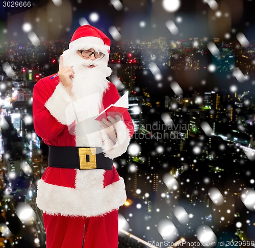 Image of man in costume of santa claus with notepad