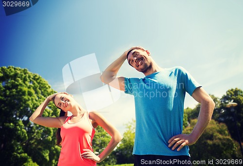 Image of smiling couple stretching outdoors