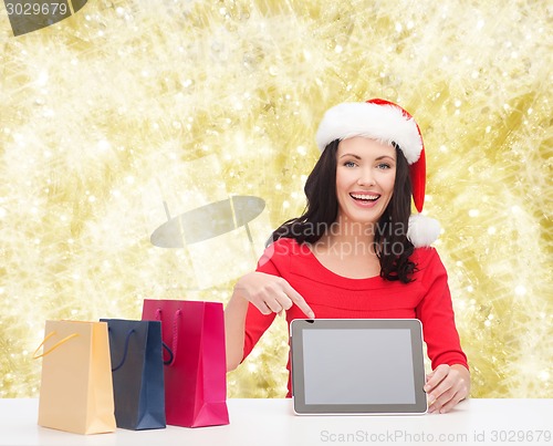 Image of smiling woman in santa hat with bags and tablet pc