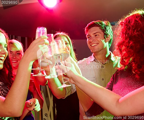 Image of smiling friends with glasses of champagne in club