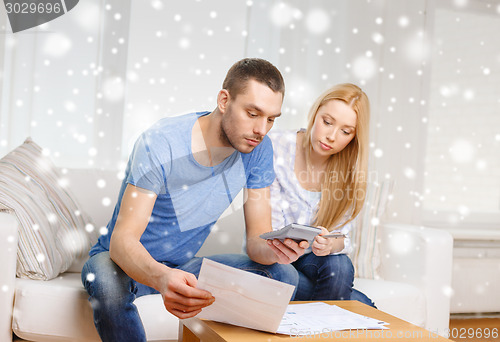 Image of busy couple with papers and calculator at home