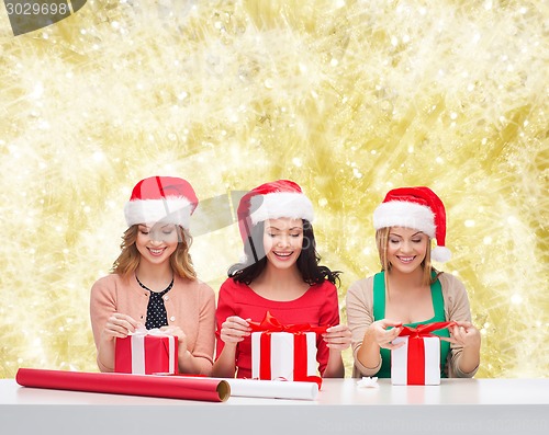 Image of smiling women in santa helper hats packing gifts