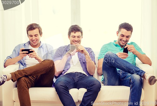 Image of smiling friends with smartphones at home