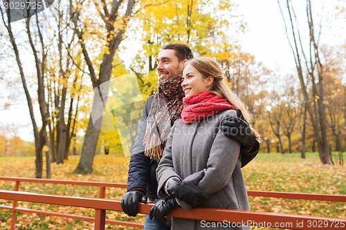 Image of smiling couple hugging on bridge in autumn park
