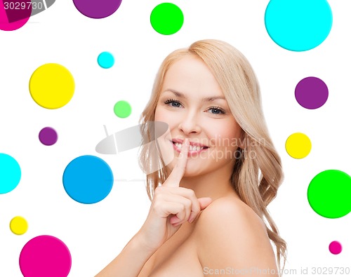 Image of beautiful young woman holding finger on lips