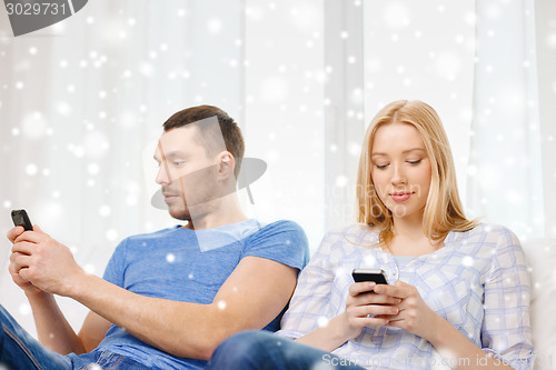 Image of couple with smartphones at home