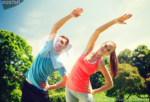 Image of smiling couple stretching outdoors