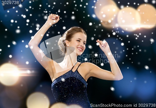 Image of smiling woman dancing with raised hands