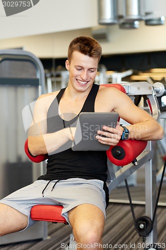 Image of smiling young man with tablet pc computer in gym