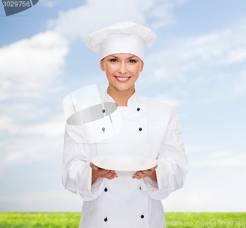 Image of smiling female chef with empty plate