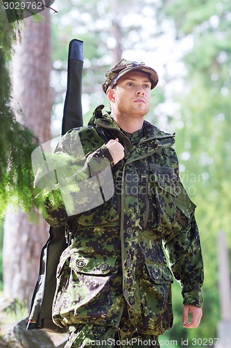 Image of young soldier or hunter with gun in forest