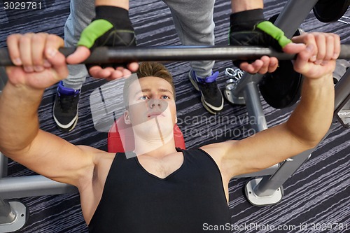 Image of men doing barbell bench press in gym