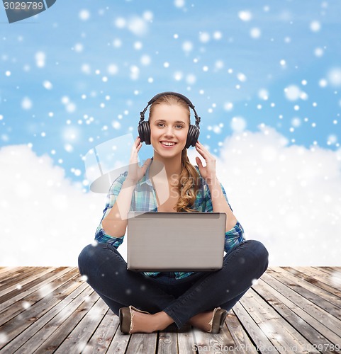 Image of happy young woman with laptop and headphones