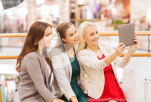 Image of happy young women with tablet pc and shopping bags