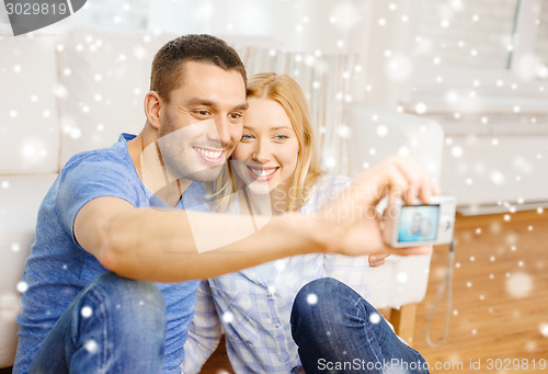 Image of smiling couple taking picture with digital camera