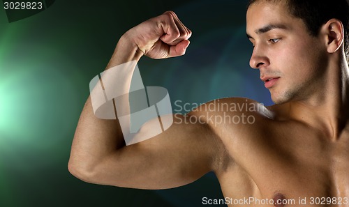 Image of close up of young man flexing and showing biceps