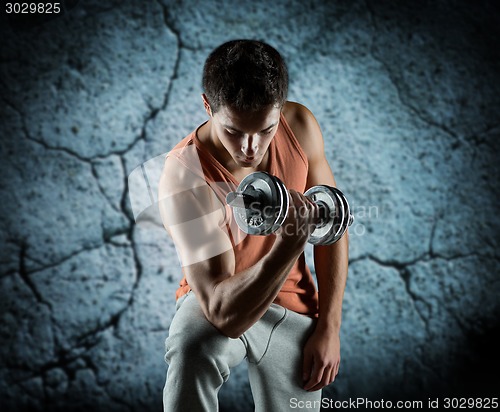 Image of young man with dumbbell flexing biceps