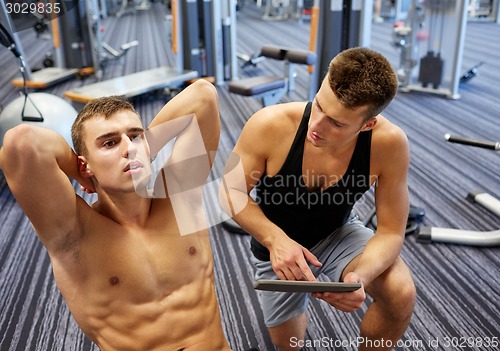 Image of men flexing abdominal muscles in gym