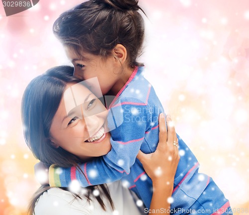 Image of smiling little girl and mother hugging indoors