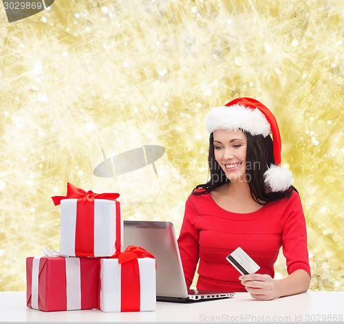 Image of smiling woman with gifts, laptop and credit card