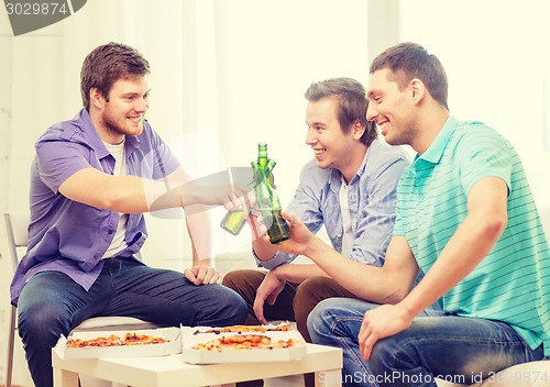 Image of smiling friends with beer and pizza hanging out