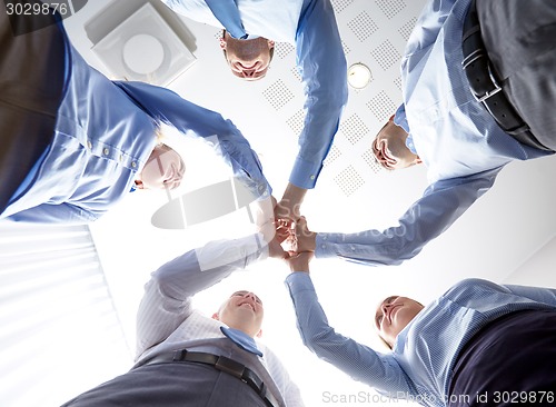 Image of smiling group of businesspeople standing in circle
