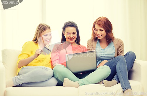 Image of smiling teenage girls with laptop and credit card