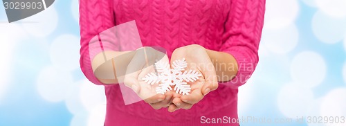 Image of close up of woman in sweater holding snowflake