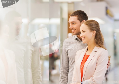 Image of happy couple looking to shop window in mall