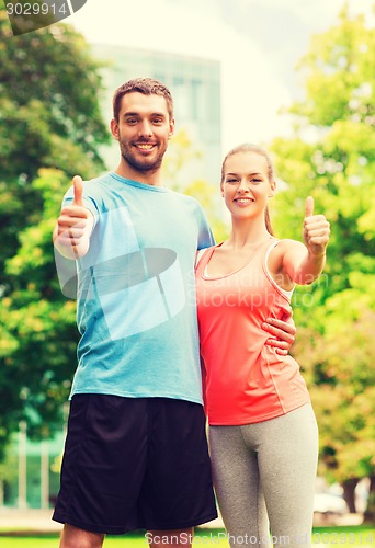 Image of smiling couple showing thumbs up outdoors