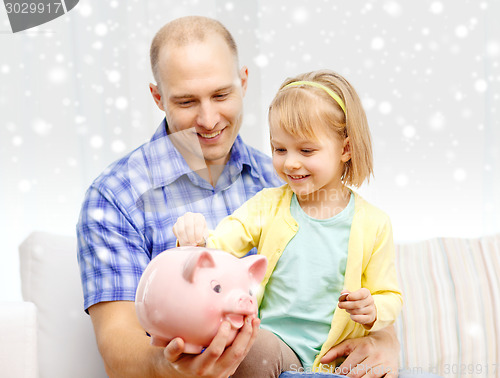 Image of happy father and daughter with big piggy bank