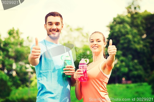 Image of smiling couple with bottles of water outdoors