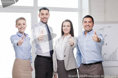 Image of business team showing thumbs up in office