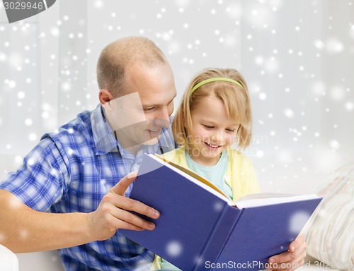 Image of smiling father and daughter with book at home