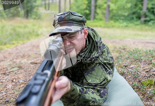 Image of close up of soldier or hunter with gun in forest