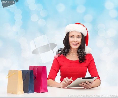 Image of smiling woman with shopping bags and tablet pc