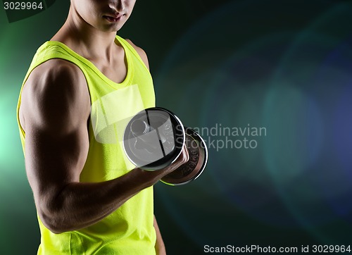 Image of close up of young man with dumbbell flexing biceps