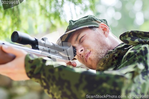 Image of young soldier or hunter with gun in forest