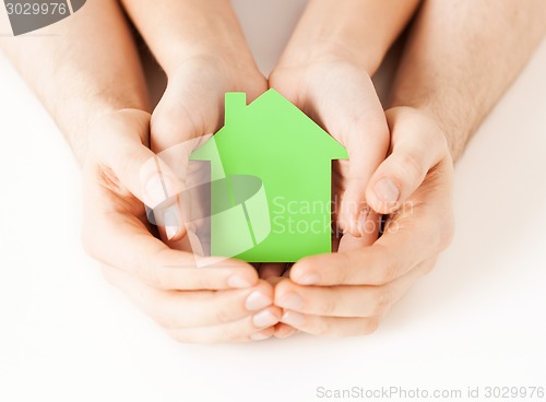 Image of man and woman hands with green paper house