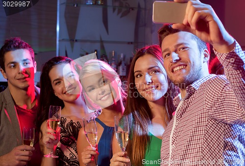 Image of friends with glasses and smartphone in club