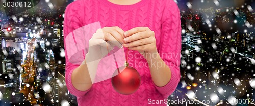 Image of close up of woman in sweater with christmas ball
