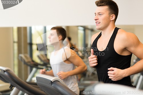 Image of smiling men exercising on treadmill in gym