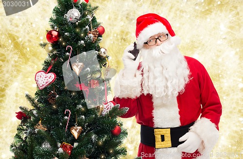 Image of santa claus with smartphone and christmas tree