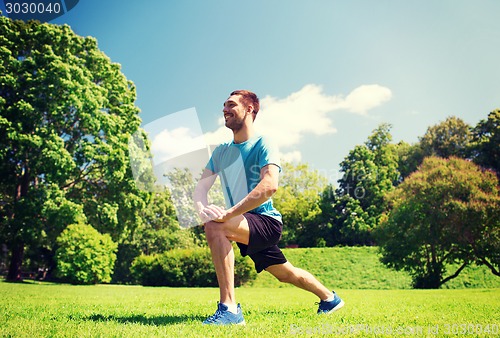 Image of smiling man stretching outdoors