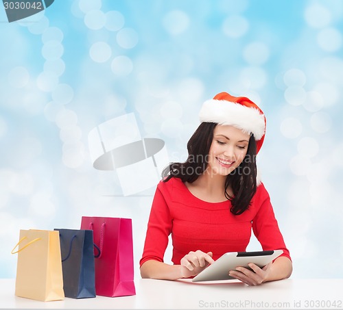 Image of smiling woman with shopping bags and tablet pc
